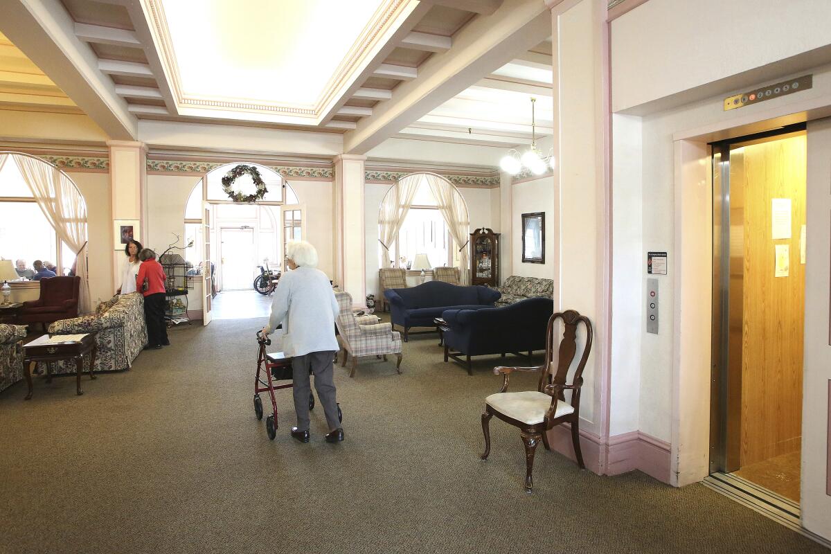 A woman uses a walker as she makes her way through a lobby in a retirement home.