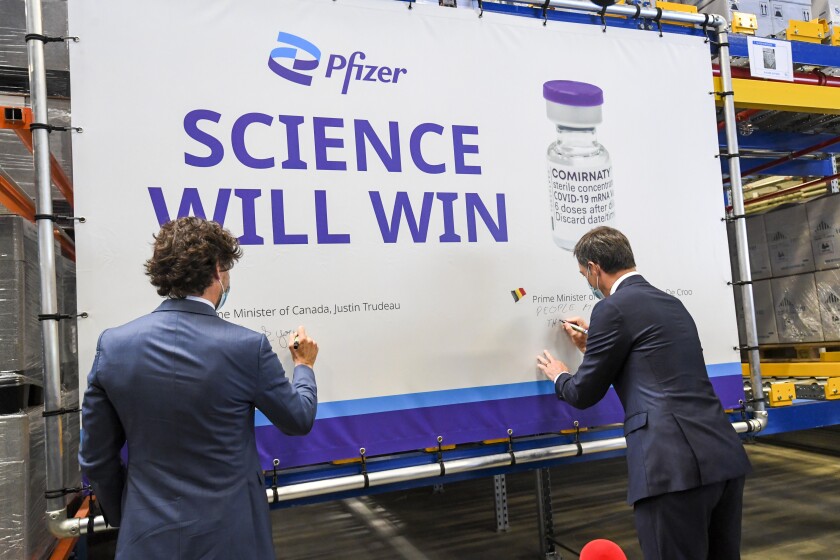 Canada's Prime Minister Justin Trudeau, left, and Belgium's Prime Minister Alexander De Croo, right, sign a banner during a working visit to the Pfizer pharmaceutical company in Puurs, Belgium, Tuesday, June 15, 2021. Canadian Prime Minister Justin Trudeau paid a visit to the Belgian Pfizer factory on Tuesday to thank employees making the COVID-19 vaccine. (Frederic Sierakowski, Pool via AP)