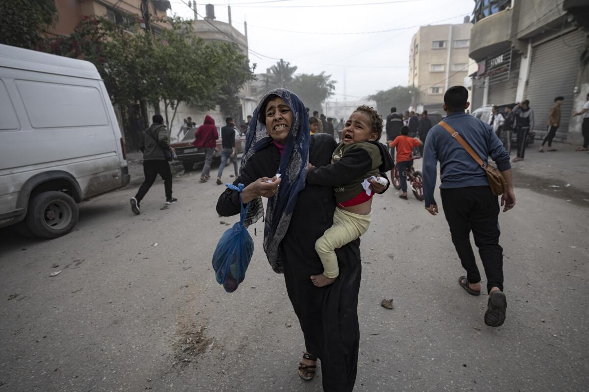 Palestinos evacúan de un sitio impactado por un bombardeo israelí en Rafah, 