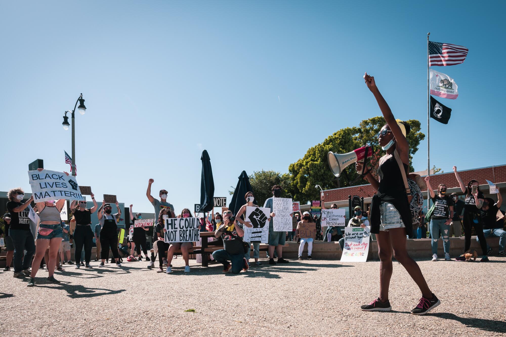 A woman in front of a crowd holds a bullhorn