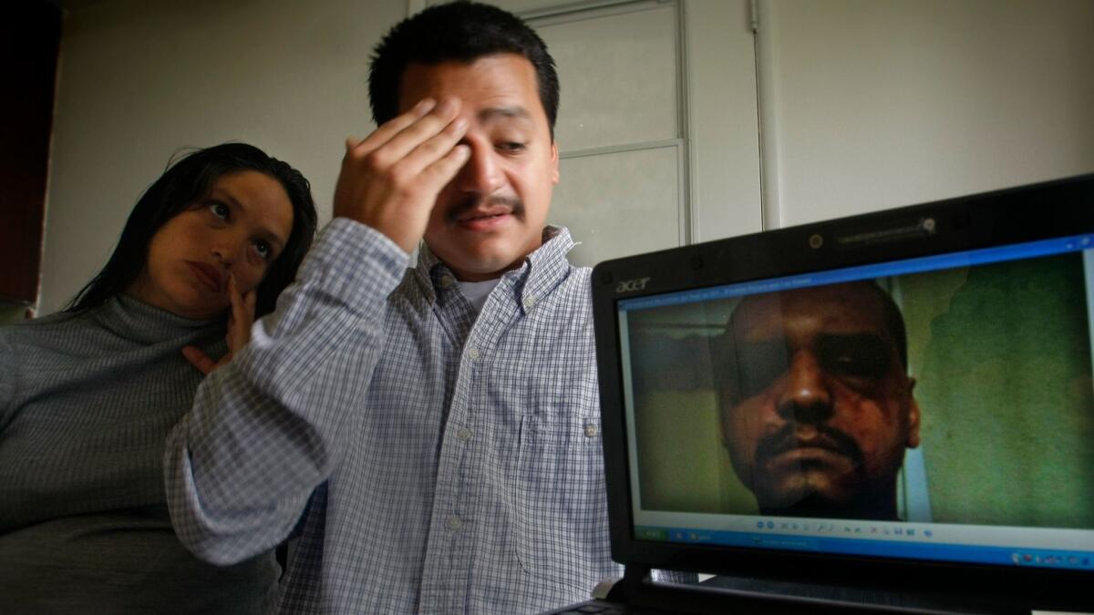 Gabriel Carrillo and his wife, Grace Martinez, with a photo she took of him after he was beaten in 2011 by Los Angeles County sheriff's deputies while visiting his brother, an inmate, at the Men’s Central Jail. Federal prosecutors won convictions against the deputies. (Don Bartletti / Los Angeles Times)