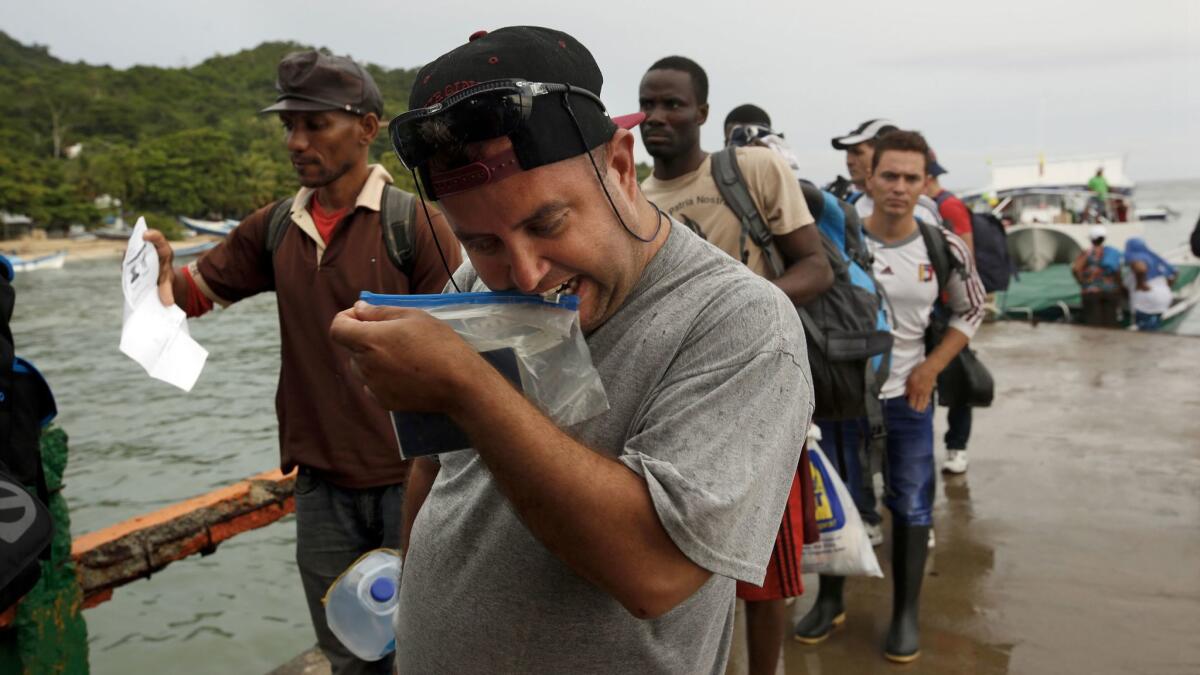 Marcelino Quintana, left, and Gutierrez, center, both from Cuba, get off a ferry in Cargurgana, Colombia, to begin their walk with other migrants to Panama.
