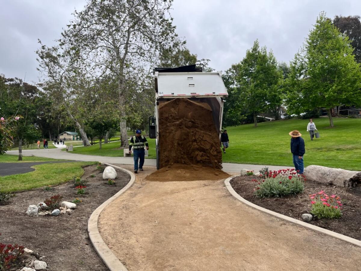 A dump truck drops fresh decomposed granite to resurface the Secret Garden at Huntington Central Park.