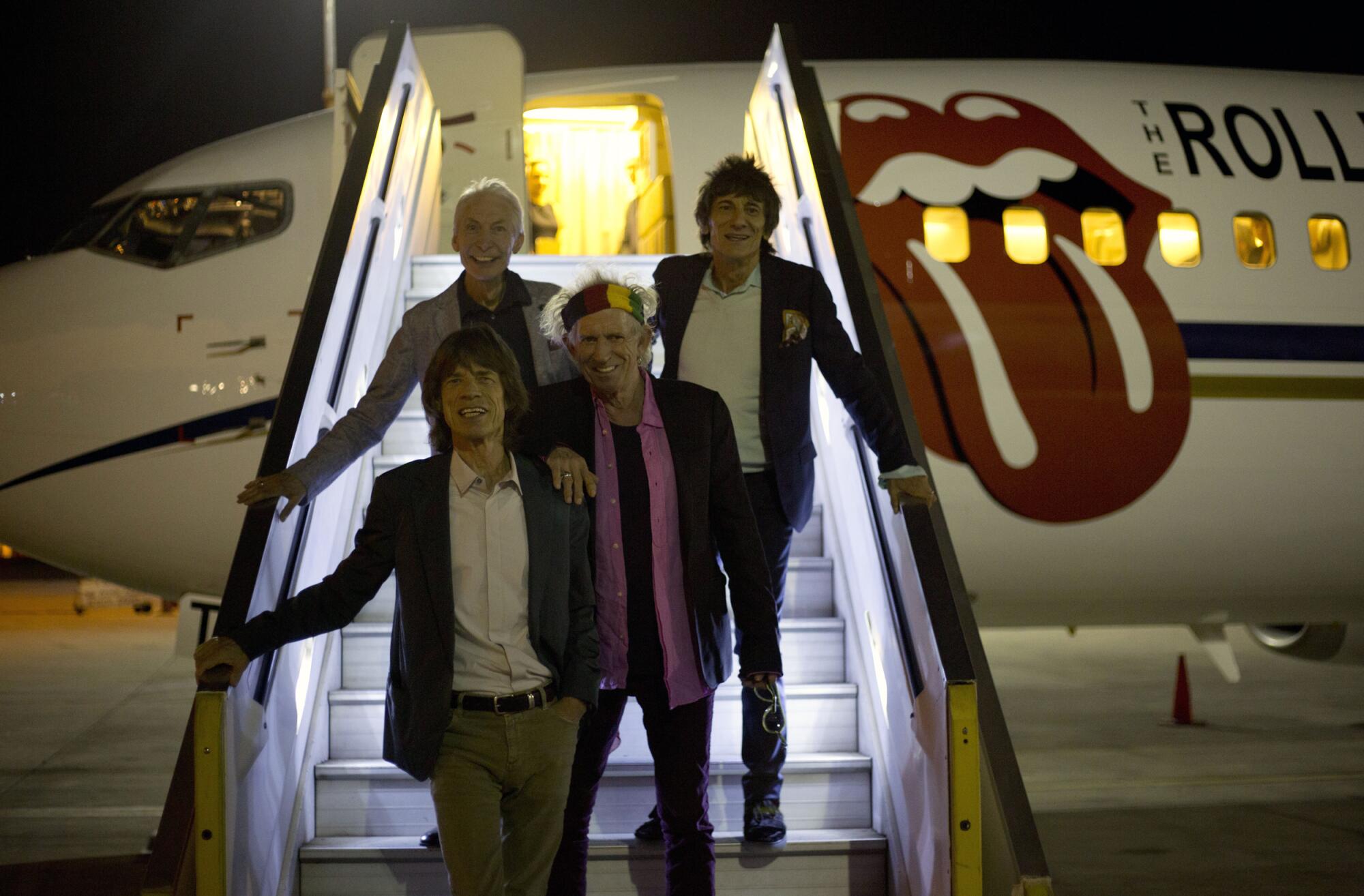 Rolling Stones singer Mick Jagger, leads the rest of the band down airplane steps.