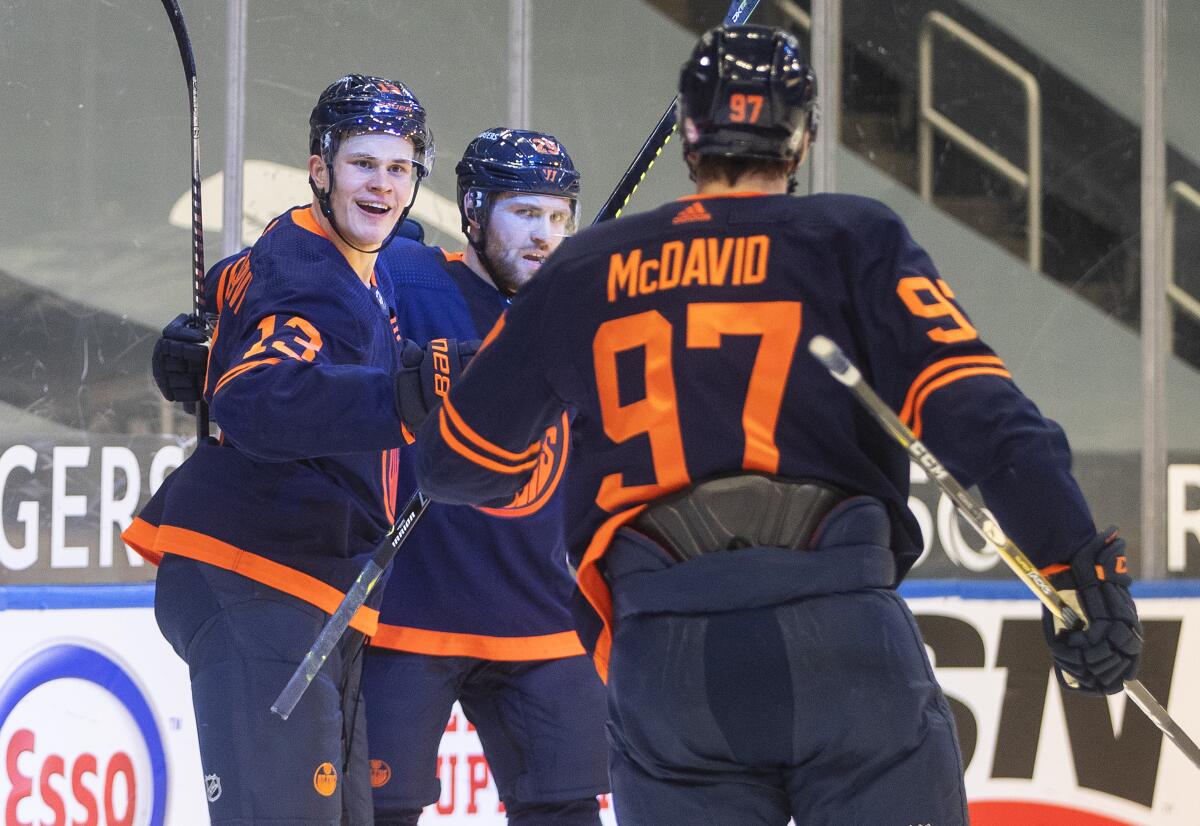 Edmonton Oilers' Jesse Puljujarvi (13), Leon Draisaitl (29) and Connor McDavid (97) celebrate a goal against the Calgary Flames during the second period of an NHL hockey game Saturday, March 6, 2021, in Edmonton, Alberta. (Jason Franson/The Canadian Press via AP)