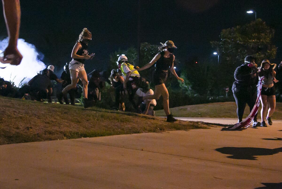 People run for cover during a protest outdoors at night