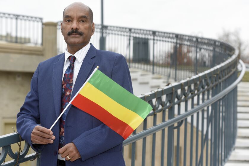 Negasi Beyene, who grew up in Mekele, the capital city of the Ethiopia's Tigray Region, holds a traditional Ethiopian flag Saturday, Dec. 18, 2021 in Columbia, Md. Beyene, who works as a biostatistician near Washington, identifies as a human rights activist for Ethiopian unity. “My motto is, ‘humanity before ethnicity.’” (AP Photo/Steve Ruark)