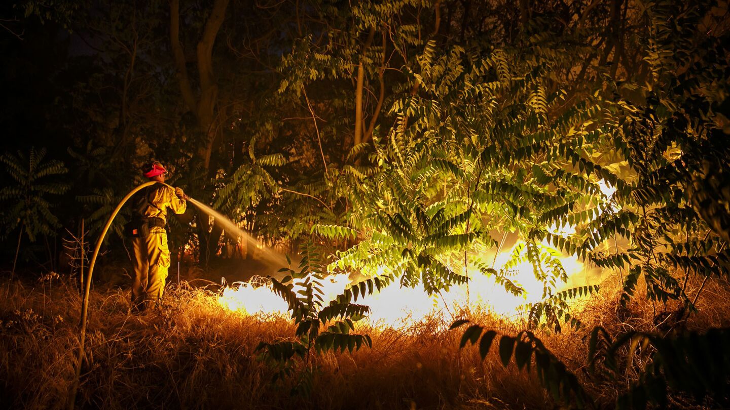 A firefighter works to defend structures on Lytle Creek Road on Wednesday night.