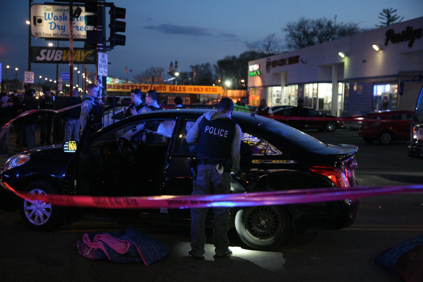 Chicago police investigate a car at 71st Street and Western Avenue, where three people were injured in a shooting that occurred near the 7900 block of South Ashland Avenue on March 8, 2016.