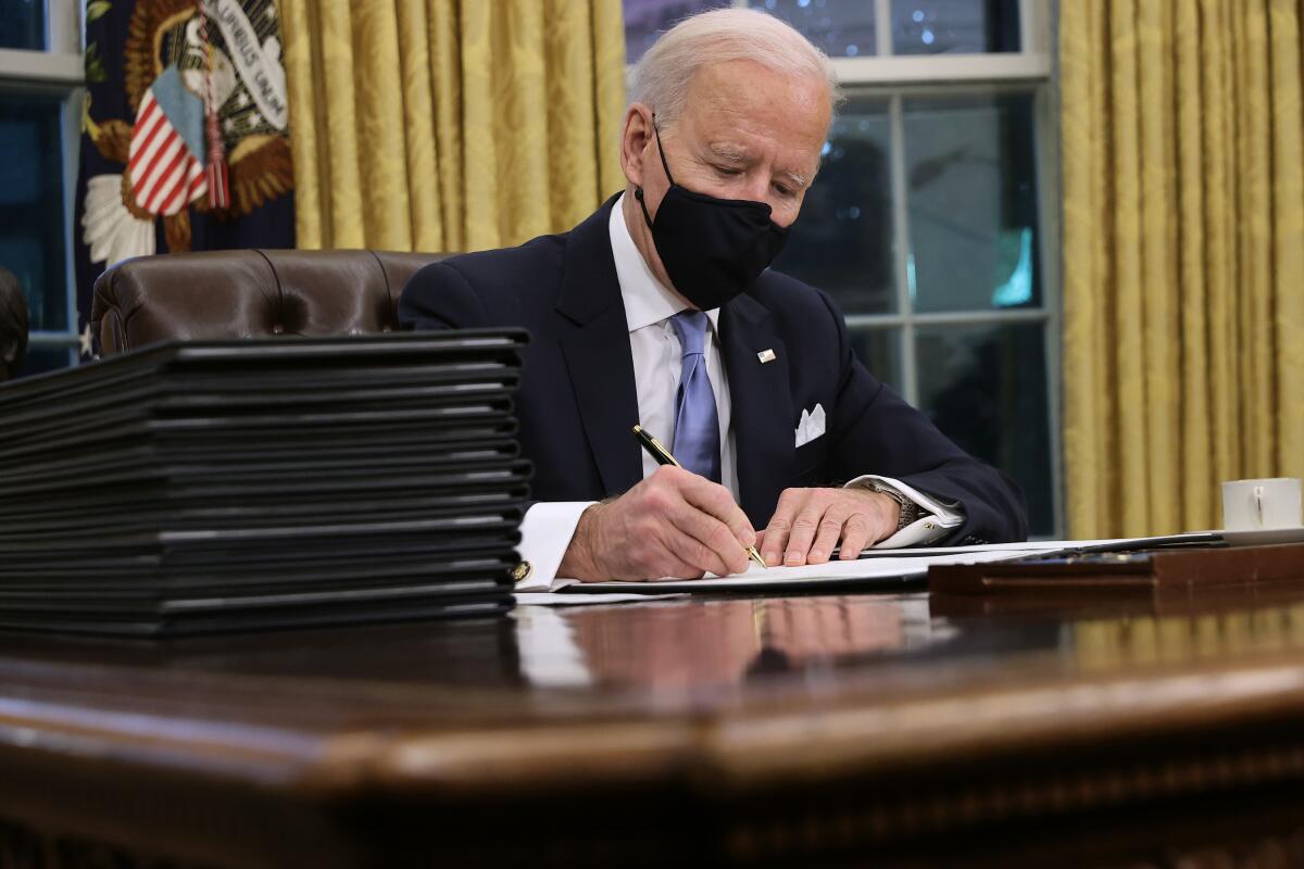 President Biden prepares to sign a series of executive orders at the Resolute Desk in the Oval Office on January 20.