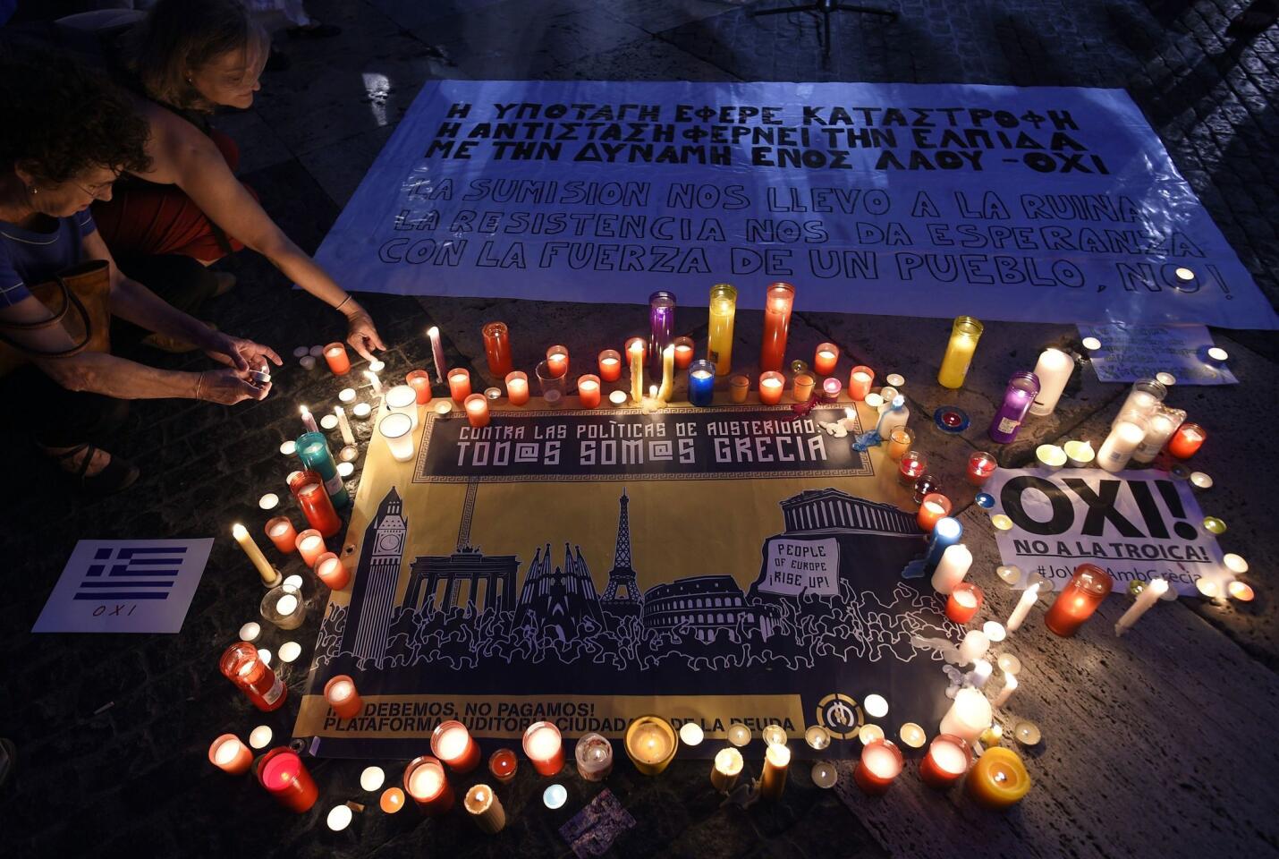 People light candles displayed next to a message as they take part in a demonstration in support of Greece, at Sant Jaume square in Barcelona on July 4, 2015 a day before nearly 10 million Greek voters take to the ballot booths to vote 'Yes' or 'No' in a referendum asking if they accept more austerity measures in return for bailout funds.