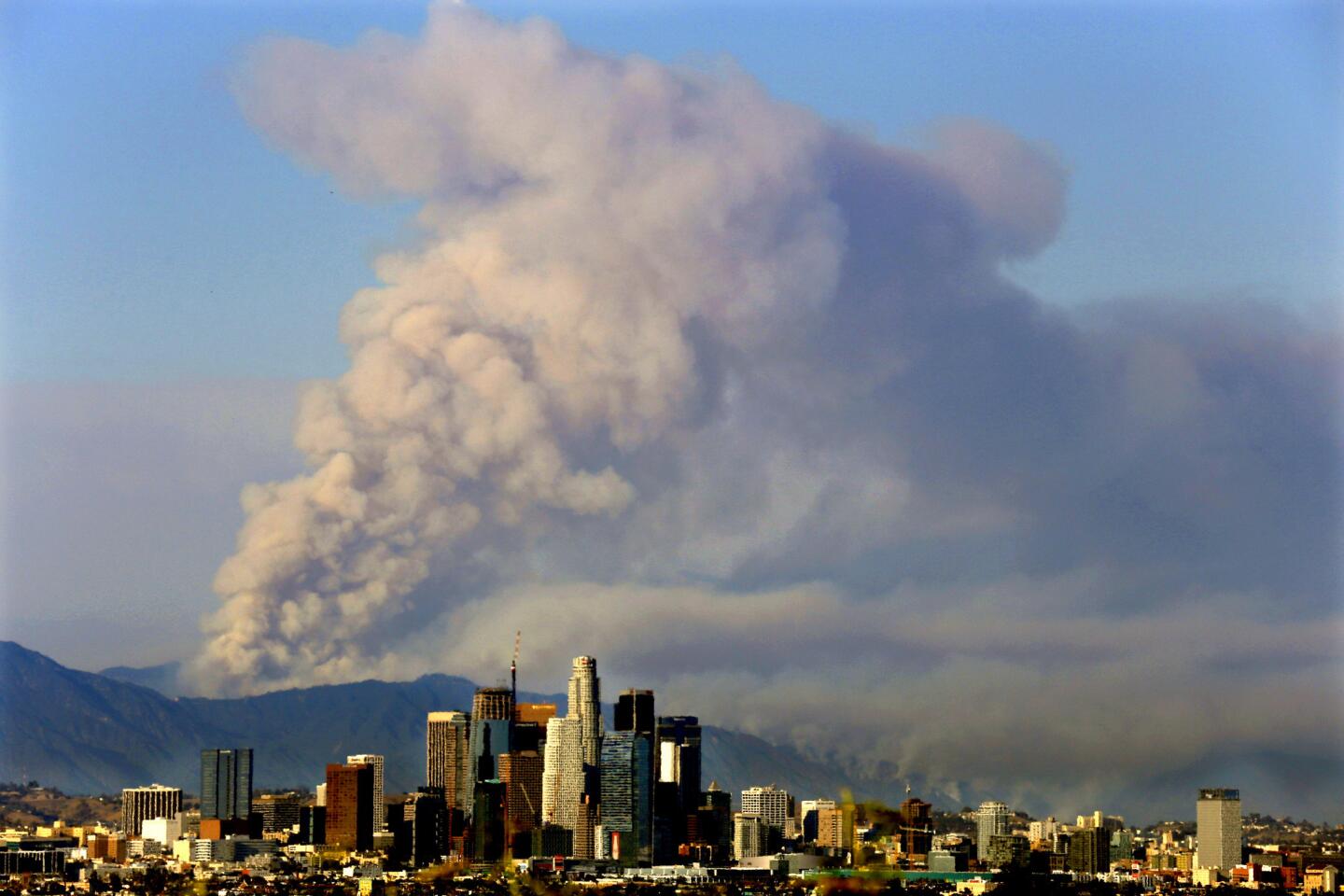 Plumes of smoke frame the Los Angeles skyline from brush fires burning above Duarte and Azusa.