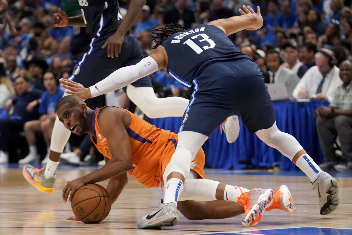 Phoenix Suns guard Chris Paul attempts to pass the ball as Dallas Mavericks' Jalen Brunson (13) attempts to avoid colliding with him in the second half of Game 4 of an NBA basketball second-round playoff series, Sunday, May 8, 2022, in Dallas. (AP Photo/Tony Gutierrez)