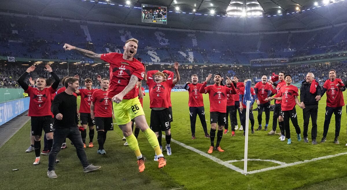 Freiburg's goalkeeper Mark Flekken jumps for joy as he celebrates with the team and fans after winning the German Soccer Cup semifinal soccer match between Hamburger SV and SC Freiburg in Hamburg, Germany, Tuesday, April 19, 2022. (AP Photo/Martin Meissner)