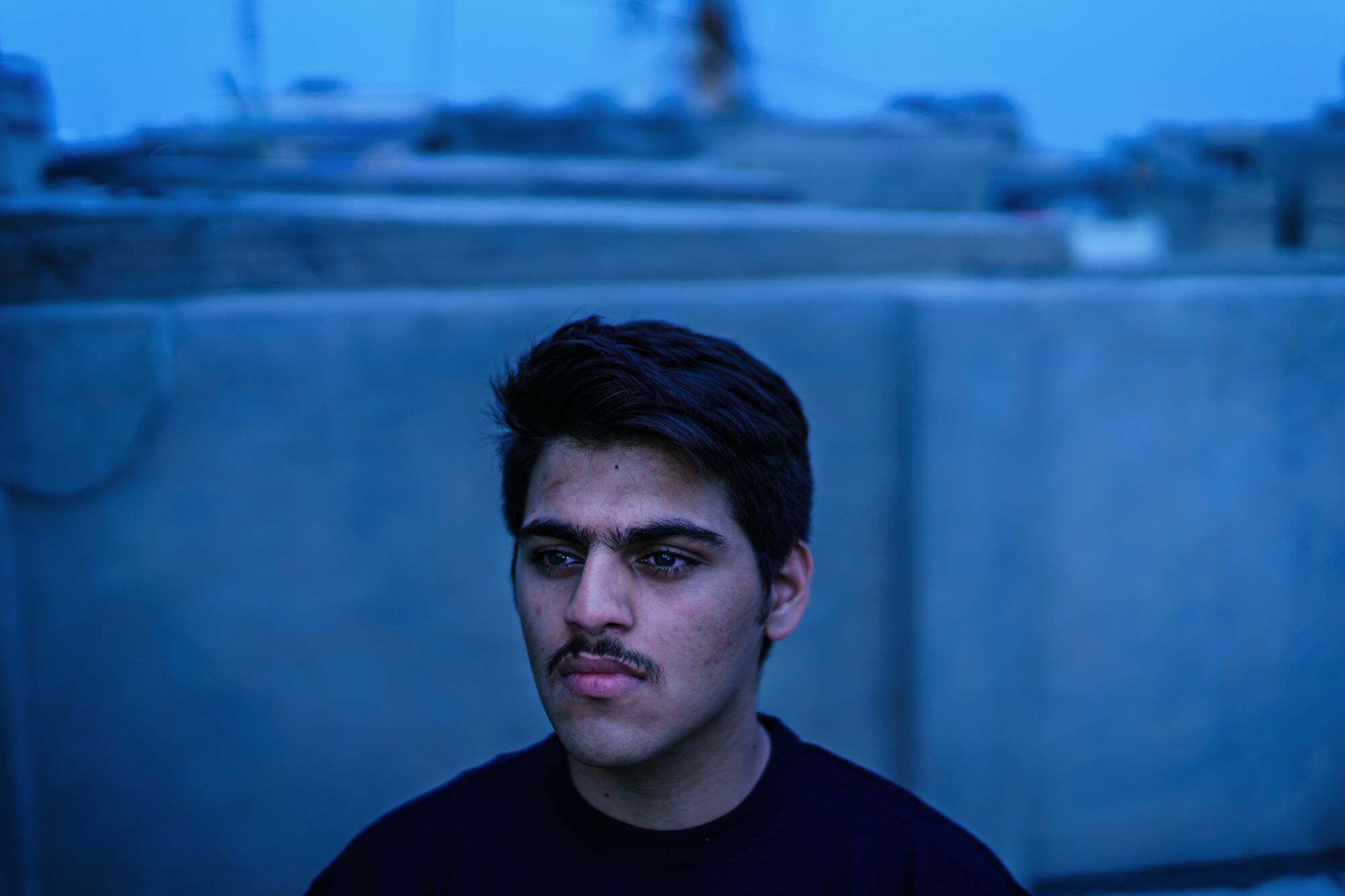 A pensive-looking young man with dark hair and mustache 