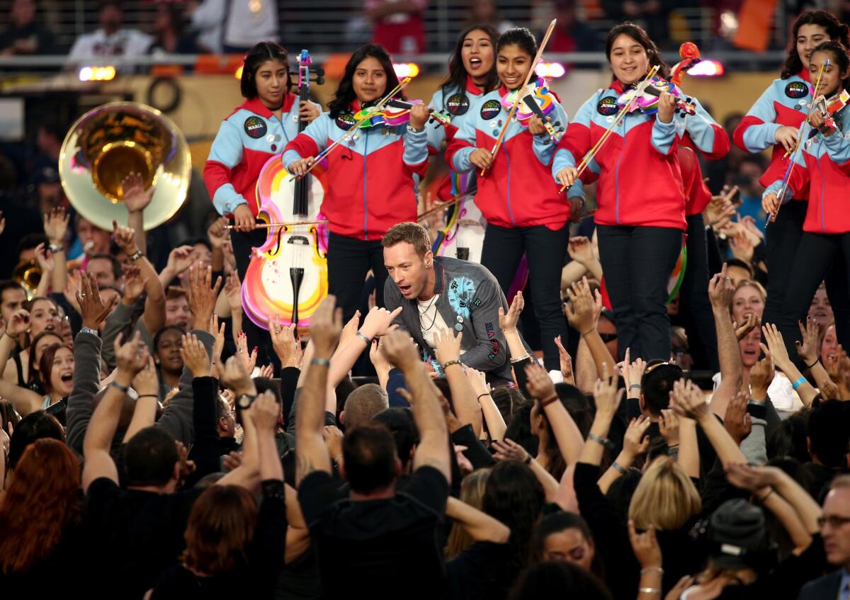 Chris Martin de Coldplay canta con YOLA tocando atrás.
