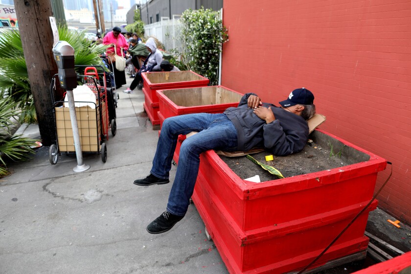 A man sleeps in a planter on South Hope Street in downtown Los Angeles.