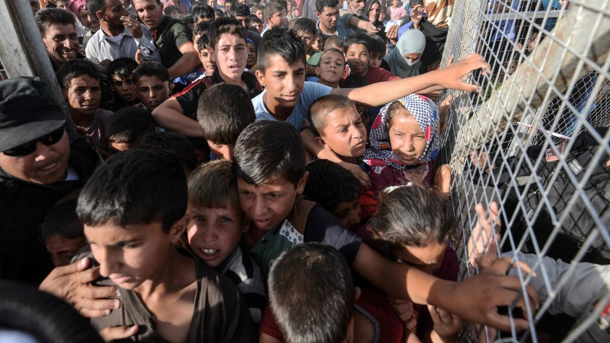 Iraqis line up behind a fence at the Hassan Sham camp for internally displaced people, 20 miles east of Mosul, in June 2017.