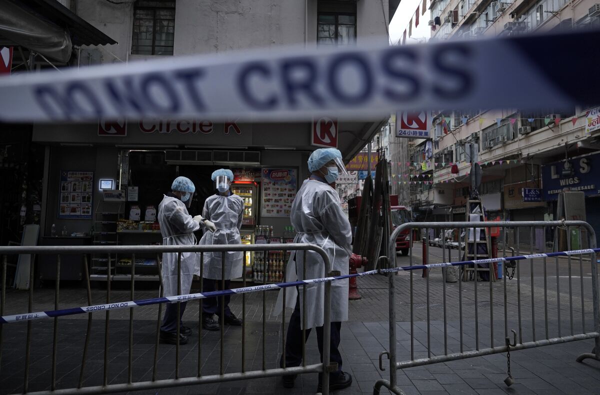 Government workers, wearing protective gear, stand guard in the Jordan district of Hong Kong in 2021.