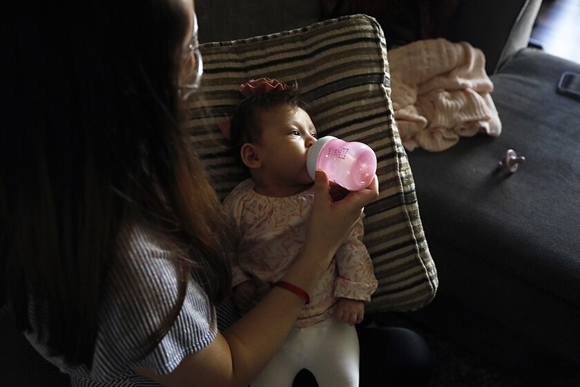 A woman bottle-feeding her 3-month-old daughter