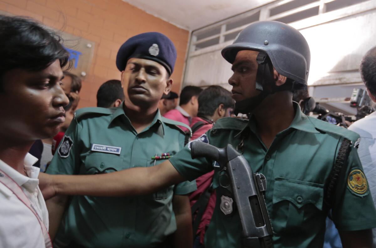 Bangladeshi policemen try to control the crowd of onlookers at a building where two people were found stabbed to death in Dhaka, Bangladesh, on Monday.