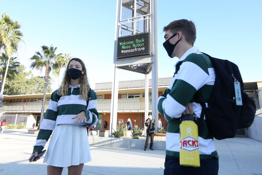 Hanna Jackson, freshman class president, and Connor Beneville, tech commissioner, greets fellow students who return to Costa Mesa High school on the first day back to school for secondary students in the Newport-Mesa Unified School District on Monday.