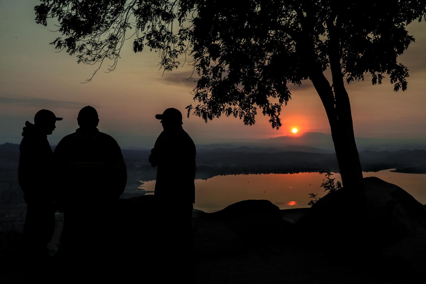 As the sun rises above Lake Elsinore on Saturday morning, the overnight crew working to contain the Holy fire prepares to leave. Containment levels have continued to rise since the fire broke out Monday.