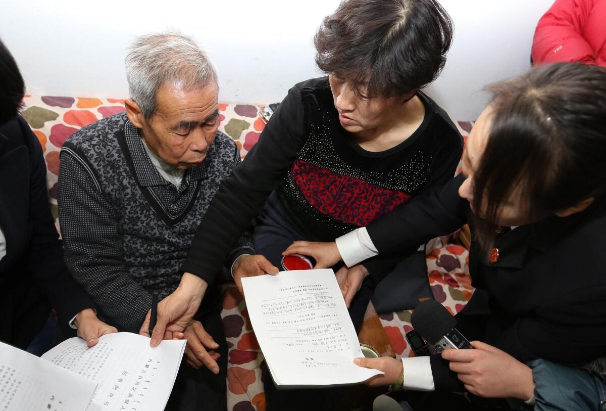 A judge of China's Supreme People's Court delivers retrial files to Huugjilt's parents, center, in Hohhot, in northern China's Inner Mongolia autonomous region, on Dec. 15. The teen, executed 18 years ago, was cleared after being wrongly convicted of murder and rape.