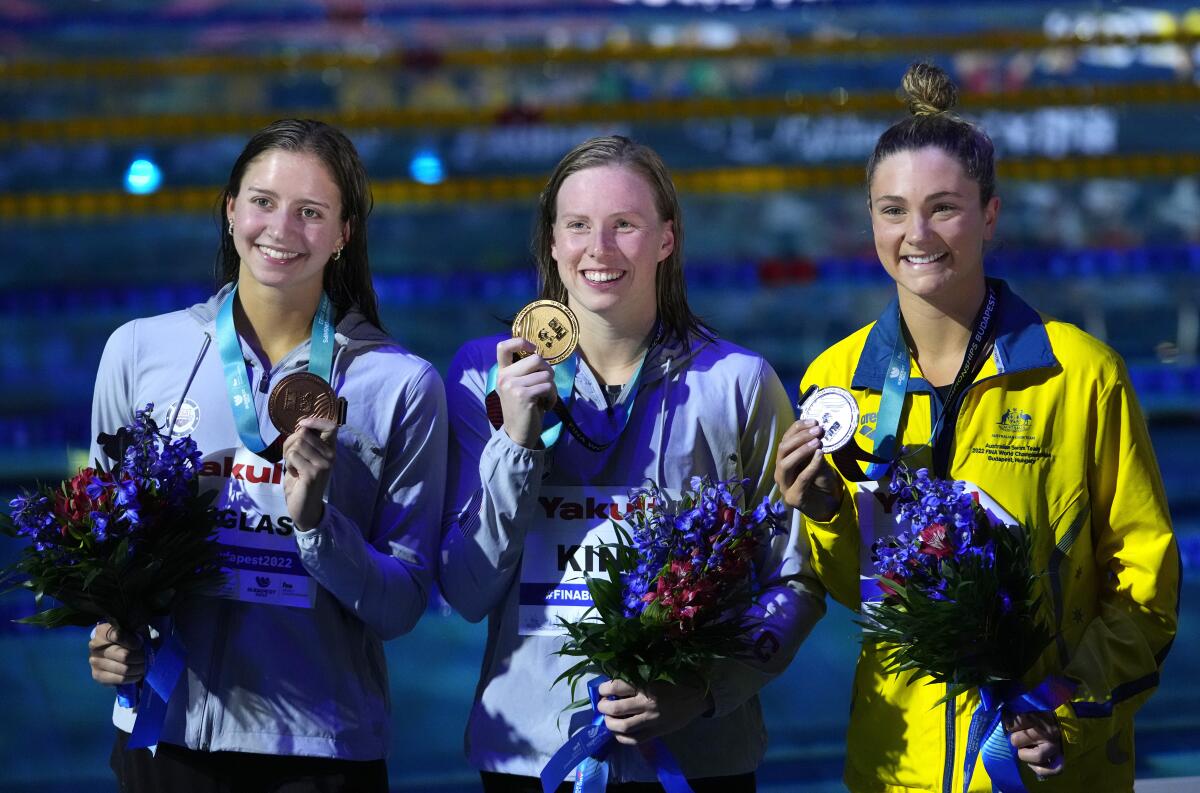 La estadounidense Lilly King, centro, posa con la presea de oro en el podio tras ganar la final de los 200 metros 