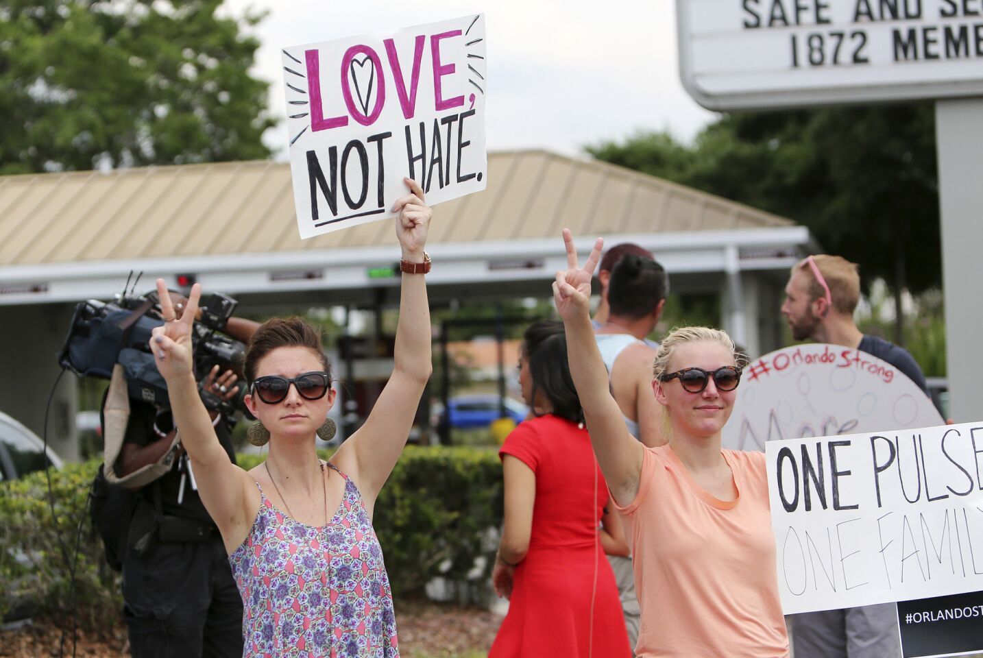 People hold signs in support of the Orlando shooting victims on Sunday.