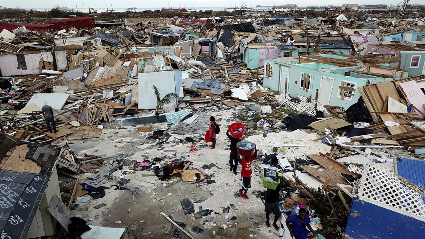 People search for salvageable items as they make their way through an area destroyed by Hurricane Dorian at Marsh Harbour in Great Abaco Island, Bahamas on Thursday, Sept. 5, 2019. (Al Diaz/Miami Herald via AP)