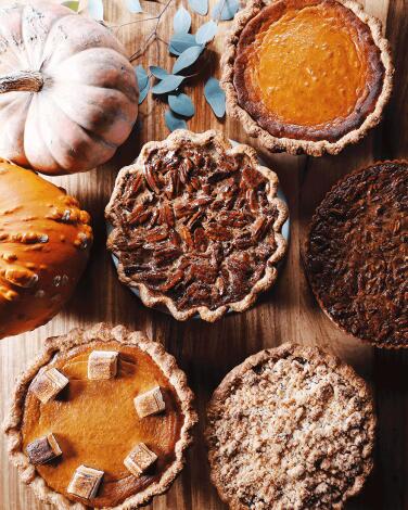 A spread of pumpkin and pecan pies with pumpkins.