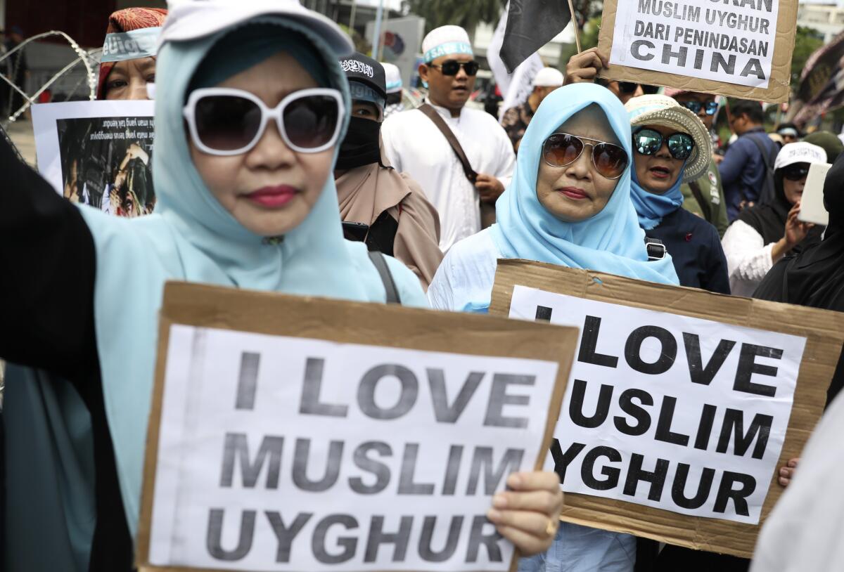 Muslim women hold posters during a rally outside the Chinese Embassy in Jakarta, Indonesia