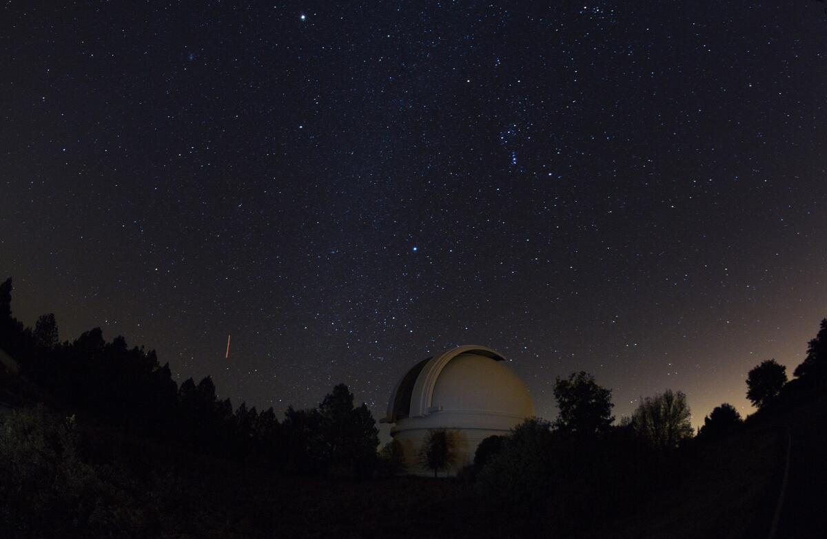 The Milky Way is the slighty brighter vertical belt of stars above the Palomar Observatory on Palomar Mountain. The streak of light to the south is the trail of an airplane during the 30-second exposure. The glow to the right is light pollution from northern San Diego County urban areas.