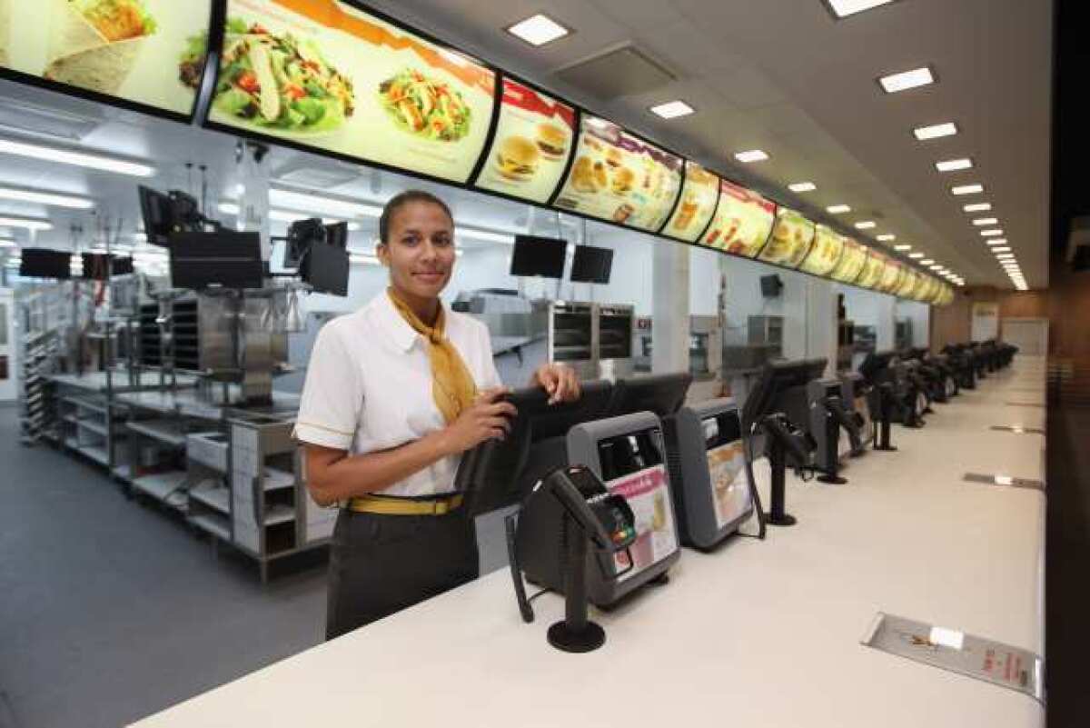 Assistant manager Rachel Lucien stands at the checkouts in the world's largest McDonald's restaurant in the Olympic Park in London, England. The fast food chain suffered a rare profit slide in its second quarter.