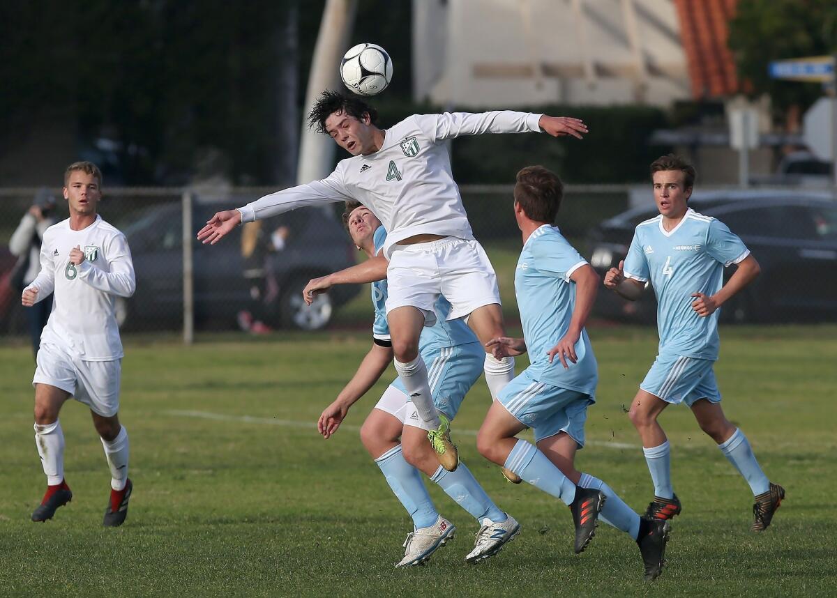 Edison's Chase Bullock (4) heads the ball while surrounded by a host of Corona del Mar defenders in a Surf League match in Newport Beach on Jan. 11.