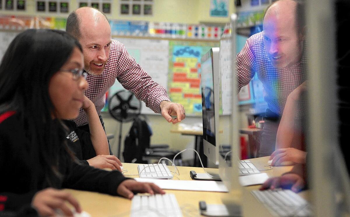 Dixon Slingerland, executive director of the Youth Policy Institute, visits with Abigail Martinez during an after-school program at Monsenor Oscar Romero Charter School, a Youth Policy Institute campus, in Los Angeles.