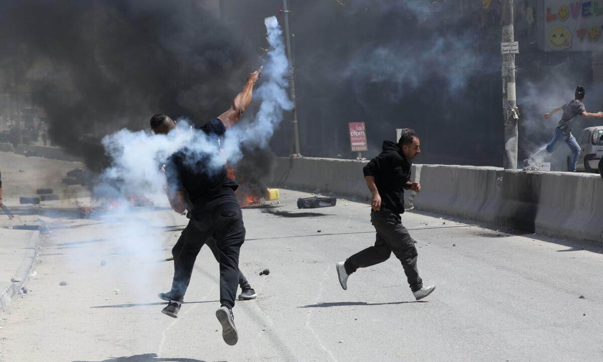 A Palestinian demonstrator throws back a tear gas grenade at the Qalandya checkpoint near the West Bank city of Ramallah on Monday.