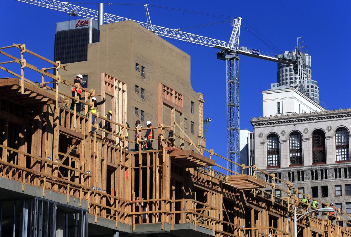 Crews work on an apartment complex under construction at Olympic Boulevard and Hill Street in downtown Los Angeles on Jan. 14.