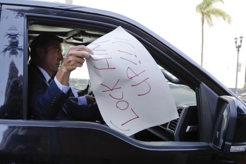 U.S. Rep. Duncan Hunter removes a sign that reads "lock him upm," placed on the windshield of his car by a protester, as he leaves an arraignment Thursday, Aug. 23, 2018, in San Diego. Hunter and his wife Margaret pleaded not guilty Thursday to charges they illegally used his campaign account for personal expenses. (AP Photo/Gregory Bull)