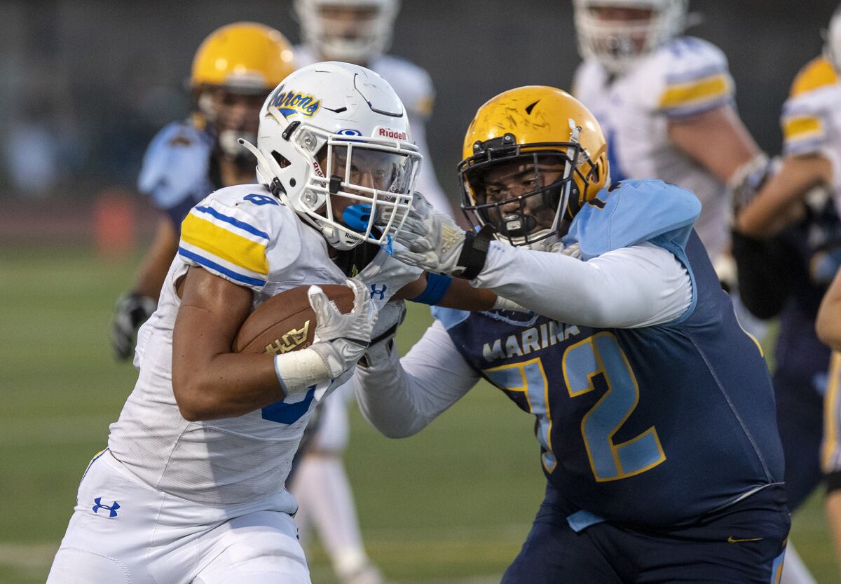 Fountain Valley's Ben Pham stiff arms Marina's Alfonso Vega in a nonleague game at Westminster High School on Sept. 10, 2021.