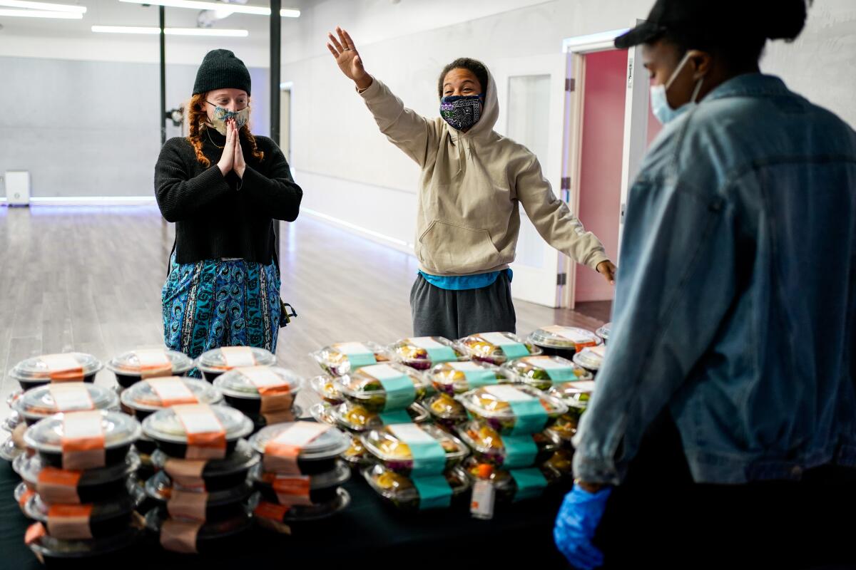 Caroline Diamond, left, and Kaileigh Williams of North Hollywood thank JaQuel Knight and volunteers during a meal giveaway event put on by Knight and Everytable at KreativMndz Dance Academy in Burbank.