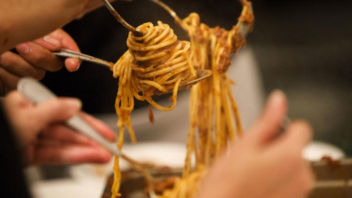 Homemade spaghetti with bolognese from Pasta Sisters is spooned onto plates.