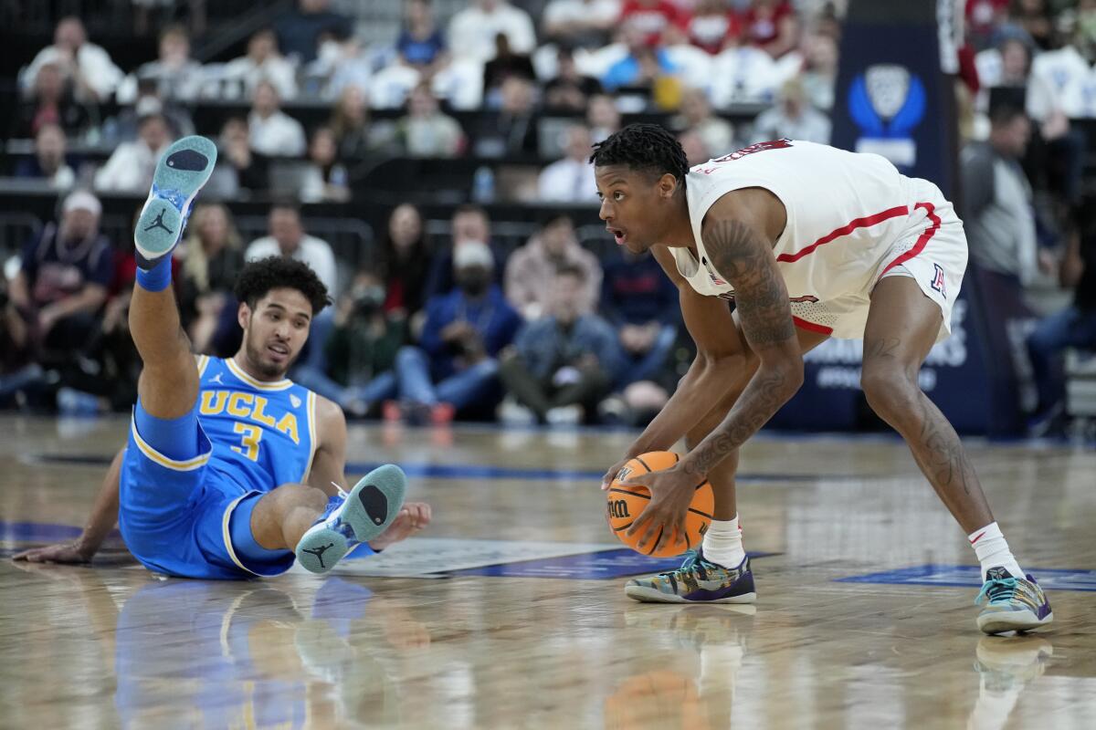 UCLA's Johnny Juzang (3) falls to the floor while scrambling for a ball with Arizona's Dalen Terry (4) during the first half.