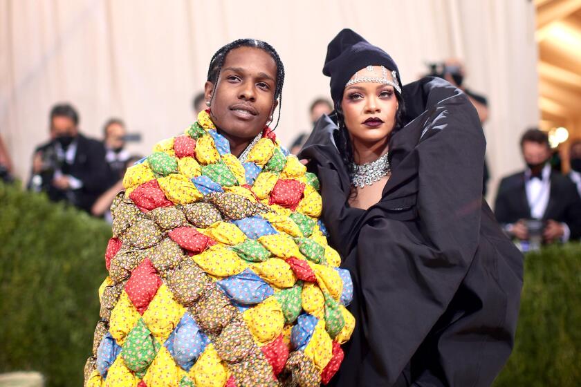 A man and a woman pose in eclectic formalwear at a gala event