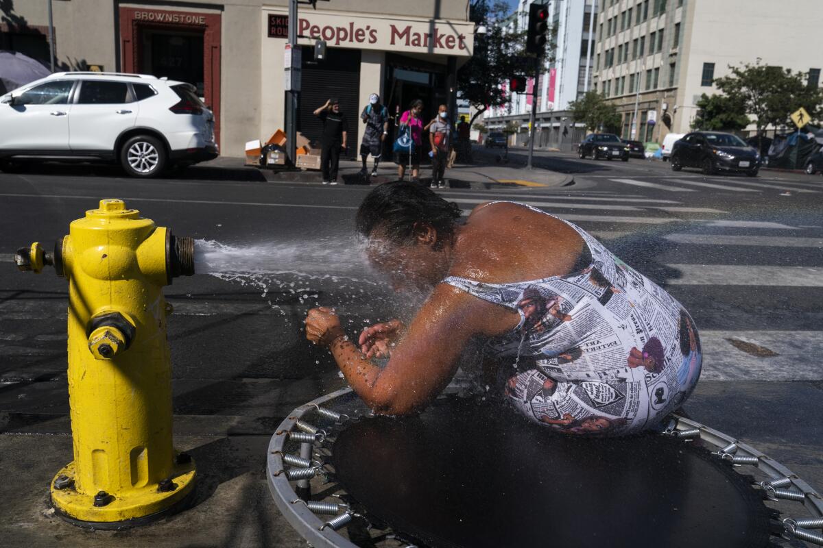 Stephanie Williams, de 60 años, se refresca con agua de un hidrante en el área de Skid Row, 