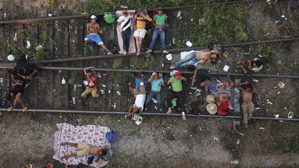 Caravan members rest on railroad tracks in southern Mexico as they slowly make their way north to seek asylum at the U.S. border.