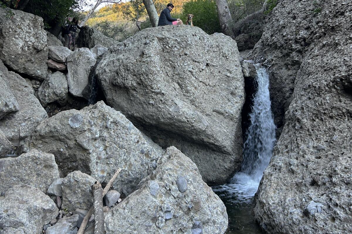 Hiker sitting on rock over a waterfall.