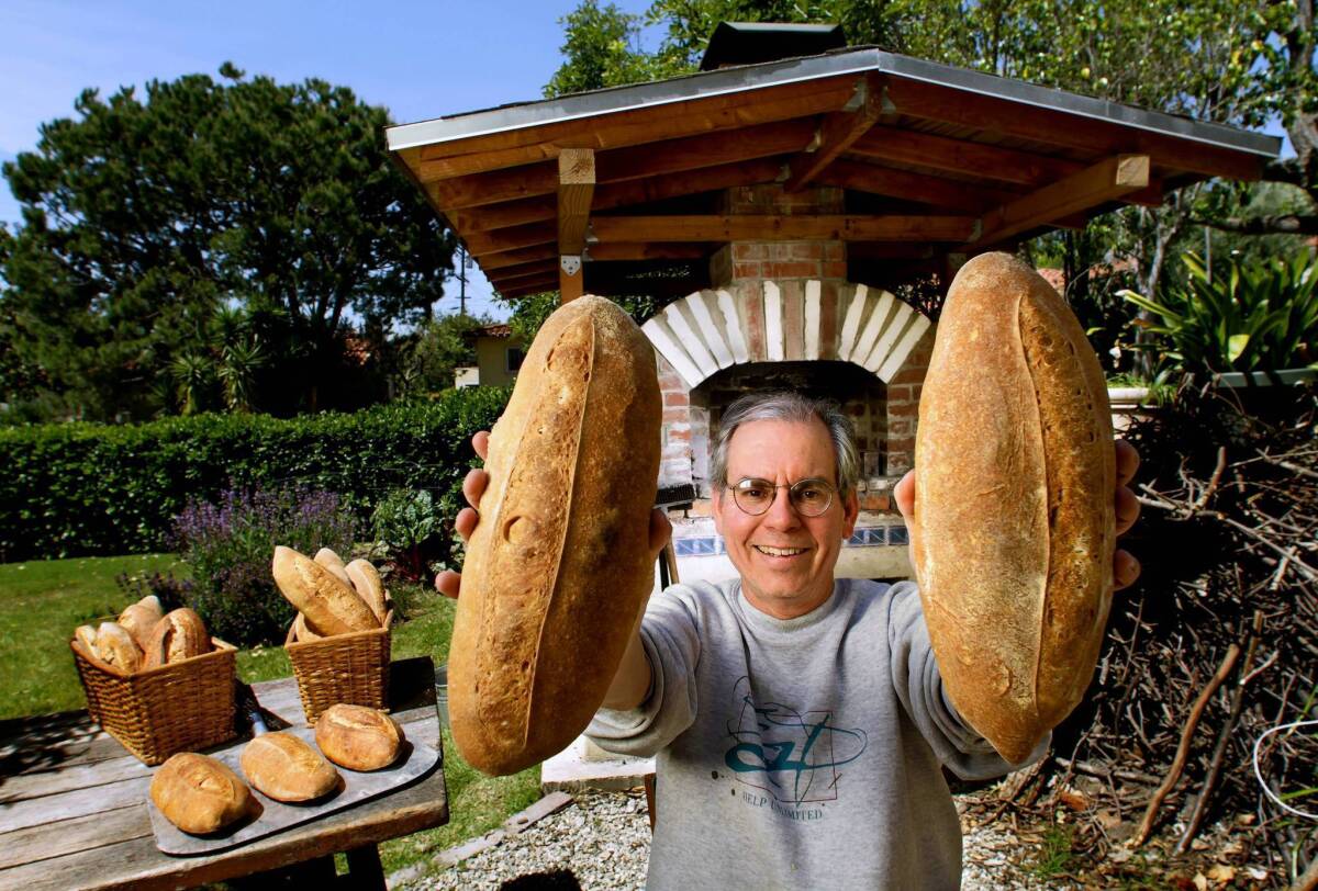 Mark Stambler shows a couple of loaves of bread he baked in his backyard wood-burning oven. He had been selling about 50 loaves a week until the Los Angeles County Health Department ordered him to stop.