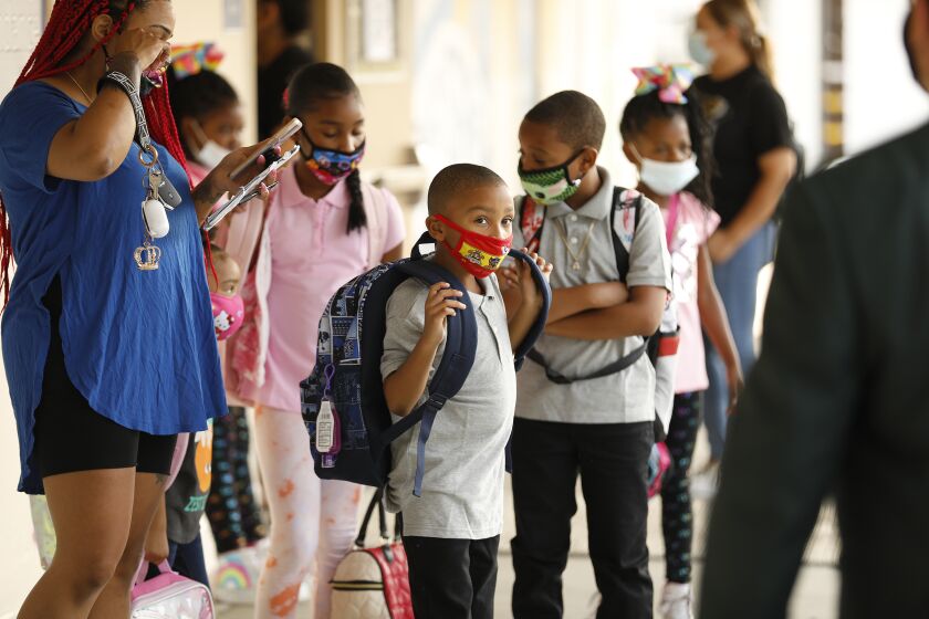 HARBOR CITY, CA - AUGUST 16: Mother Ladayna Jordan, left, leads her children, Alayna, Aedan, Aaliyah and Ahmier Davis, left to right, to the front door of Normont Elementary School on the first day of in class instruction on August 16, as LAUSD officials welcome students, teachers, principals, at various school sites across Los Angeles. For the younger students it will be their first time in a classroom. Normont Elementary on Monday, Aug. 16, 2021 in Harbor City, CA. (Al Seib / Los Angeles Times).